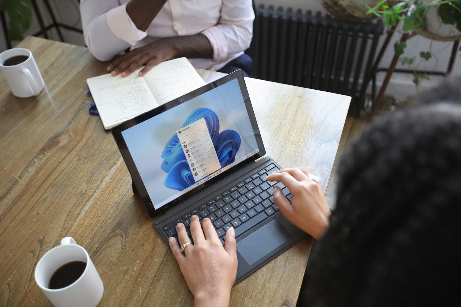 Medewerker typt op een laptop met een kop koffie ernaast